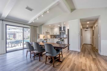 a dining room with a table and chairs in front of a kitchen with a door